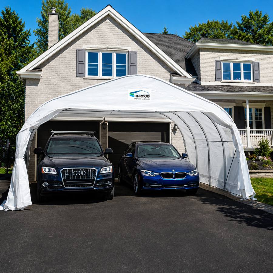 Abri d'auto double XR Harnois installé devant une maison avec deux véhicules à l'intérieur